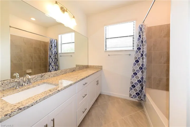 Full bathroom with vanity, shower / bath combination with curtain, plenty of natural light, and light tile patterned floors