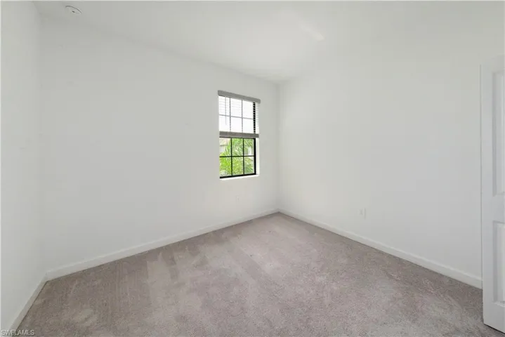Unfurnished room featuring light carpet and baseboards
