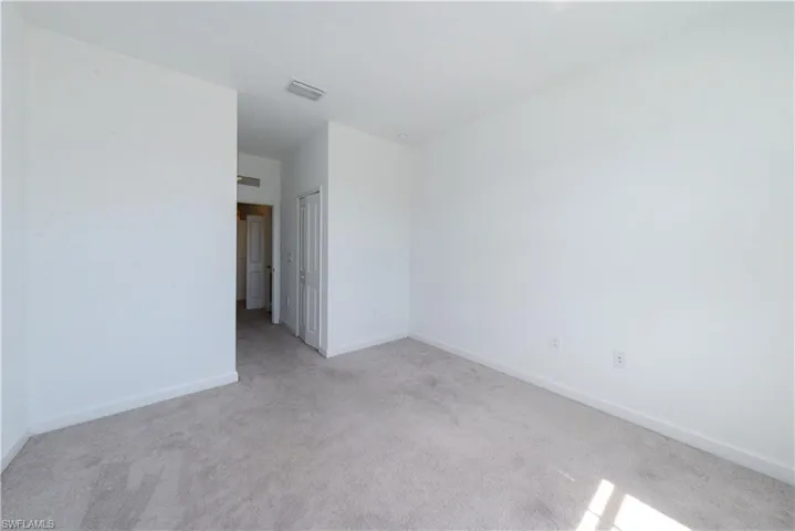 Unfurnished room featuring light carpet and baseboards