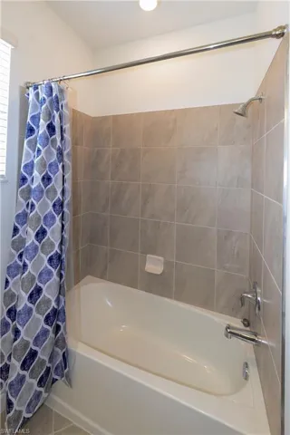 Full bath featuring shower / bath combination with curtain and tile patterned flooring