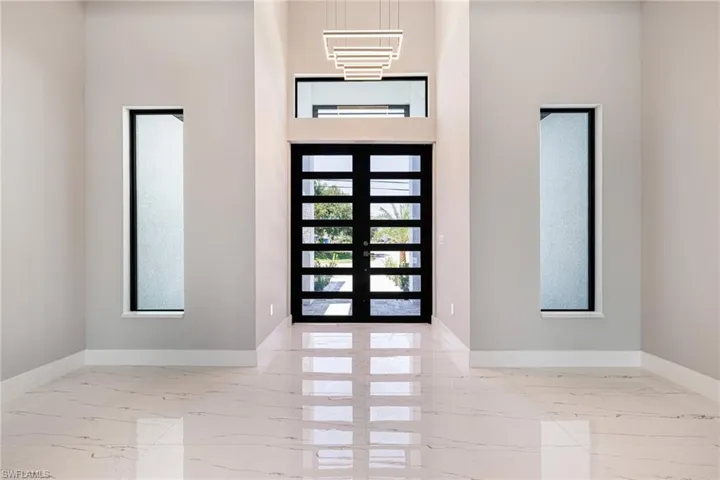 Entryway with marble tiled flooring, baseboards, french doors, and a towering ceiling