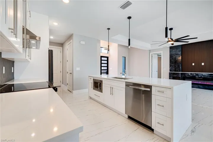 Kitchen featuring appliances with stainless steel finishes, light marble finish floors, ceiling fan, white cabinetry, and recessed lighting