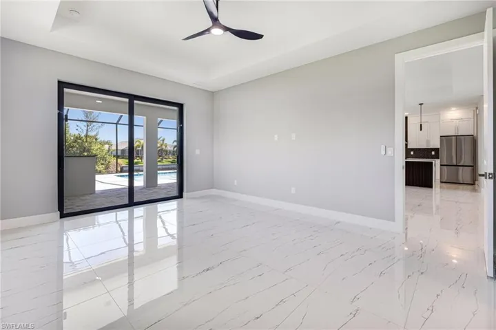 Spare room featuring baseboards, light marble finish floors, ceiling fan, and a raised ceiling