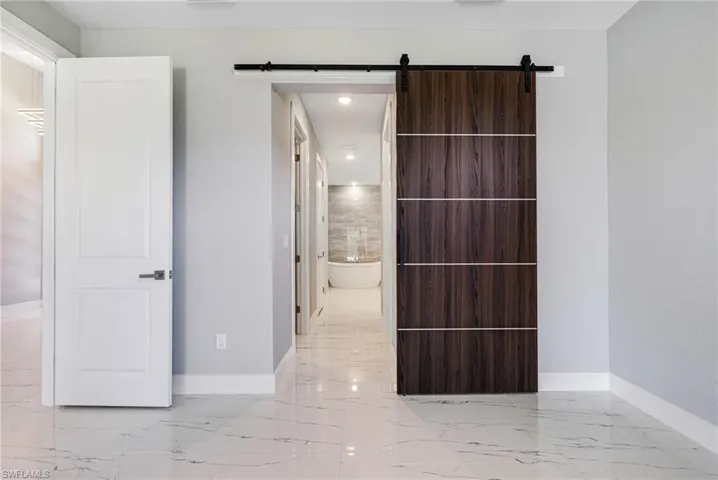 Hallway featuring marble tiled flooring, baseboards, a barn door, and recessed lighting
