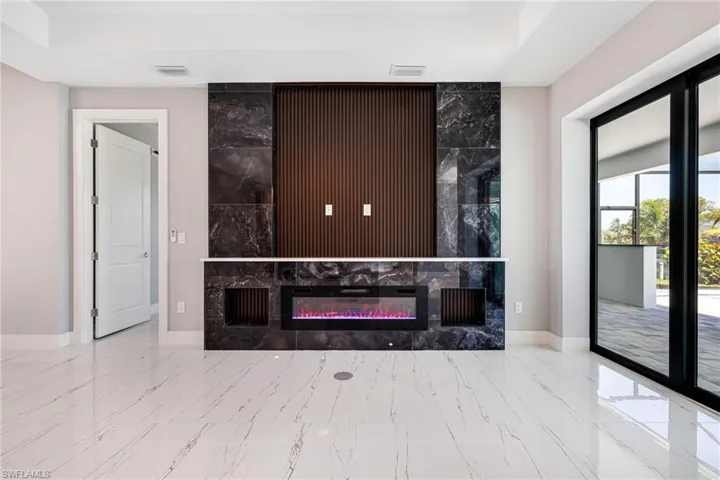 Living area with marble look tile flooring, baseboards, a fireplace, and a raised ceiling
