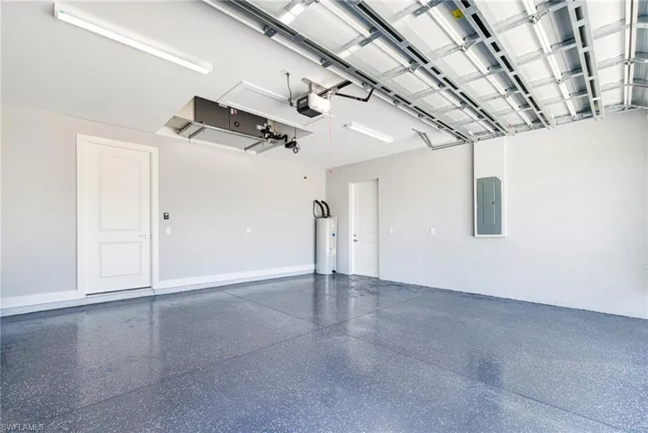 Garage featuring water heater, a garage door opener, and electric panel