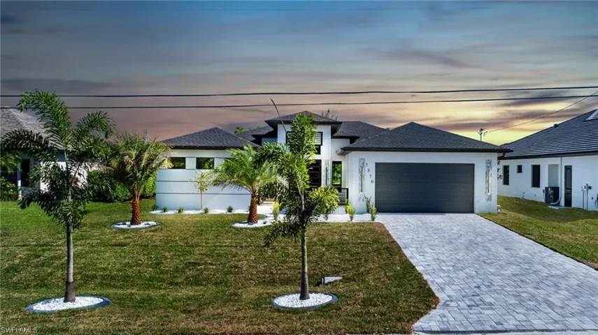 View of front of house featuring a garage, decorative driveway, stucco siding, a front yard, and roof with shingles