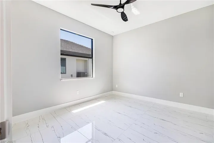 Spare room with ceiling fan, marble finish flooring, and baseboards