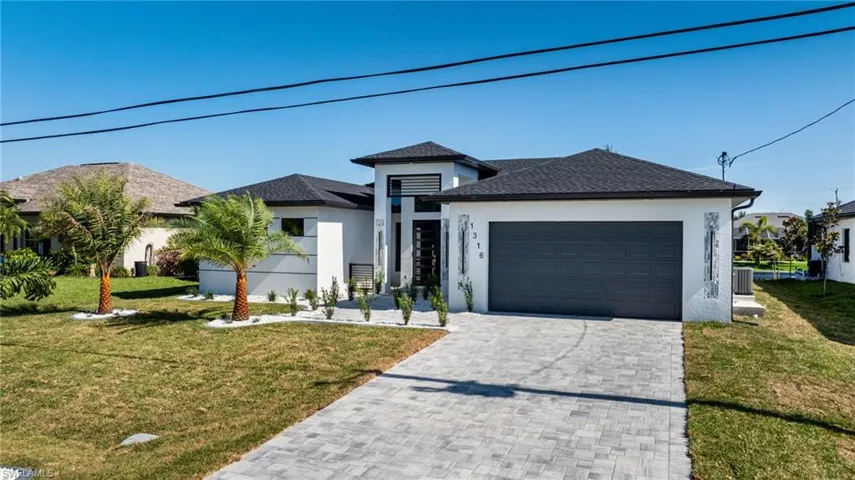 View of front of property with stucco siding, an attached garage, a front yard, and decorative driveway