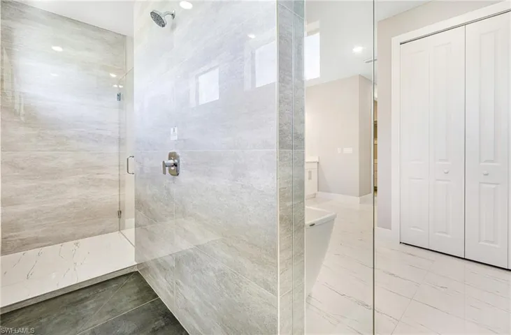 Full bathroom featuring a shower stall, a closet, and marble finish floors