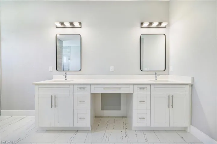 Full bathroom featuring marble look tile flooring, baseboards, and double vanity