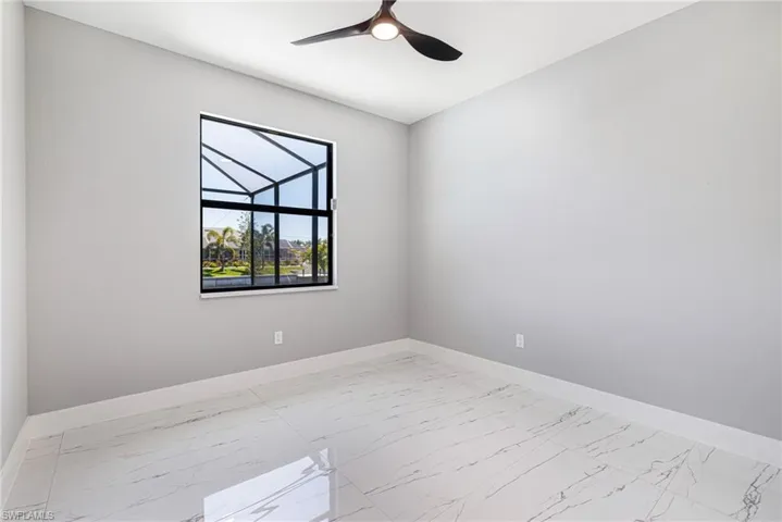Spare room with baseboards, light marble finish floors, and ceiling fan