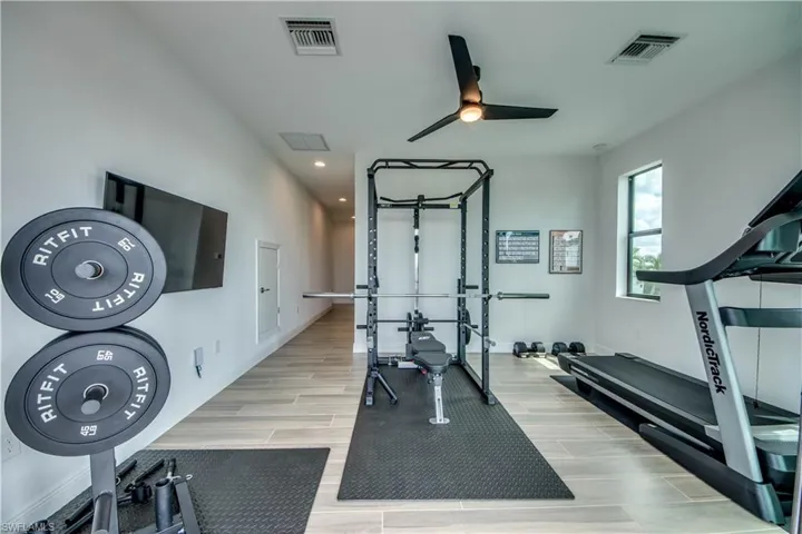 Exercise area featuring wood tiled floors, ceiling fan, and recessed lighting