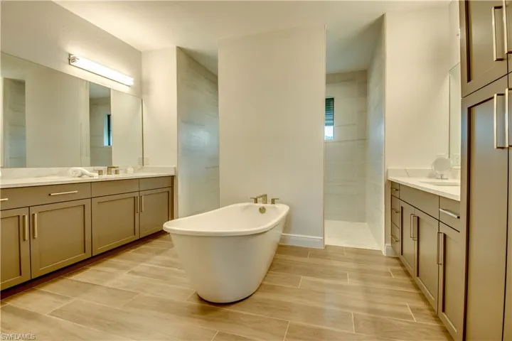 Bathroom with a soaking tub, walk in shower, two vanities, and wood tiled floors