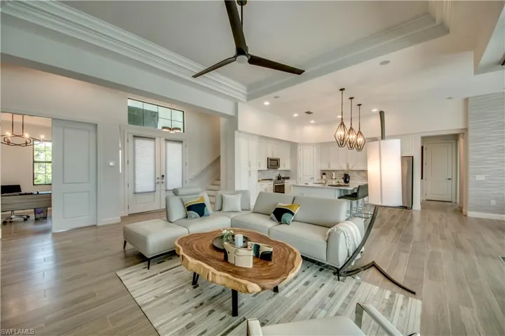 Living area with a chandelier, crown molding, wood tiled floors, stairway, and ceiling fan