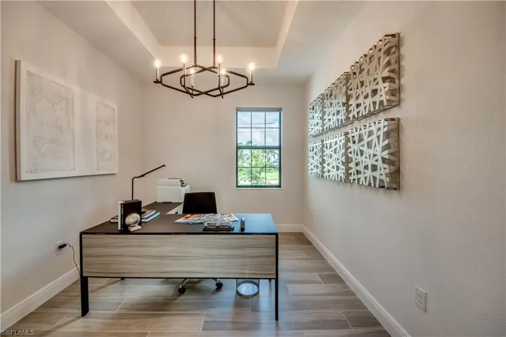 Office space with wood finish floors, a tray ceiling, and a chandelier