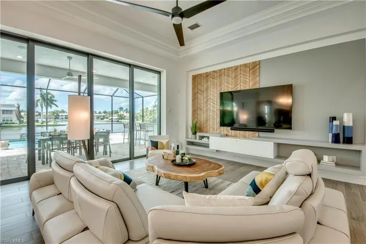 Living room with wood tiled floors, a sunroom, a ceiling fan, and crown molding