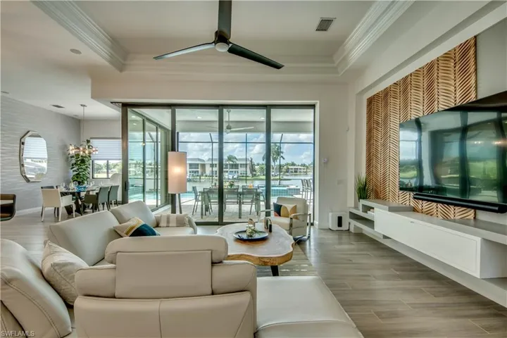 Living area with wood tiled floors, plenty of natural light, ornamental molding, and ceiling fan
