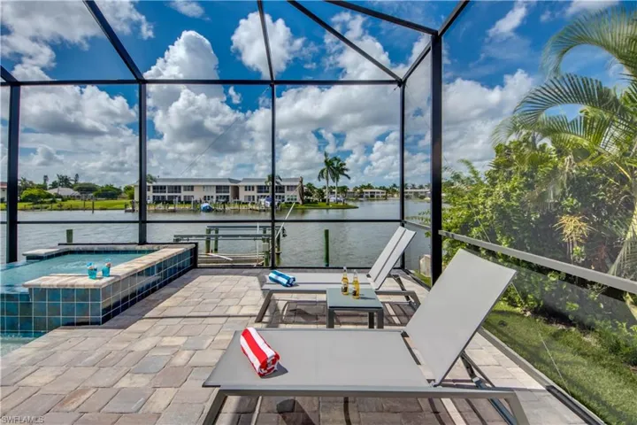 View of patio / terrace with a sunroom, a jacuzzi, a lanai, and a water view