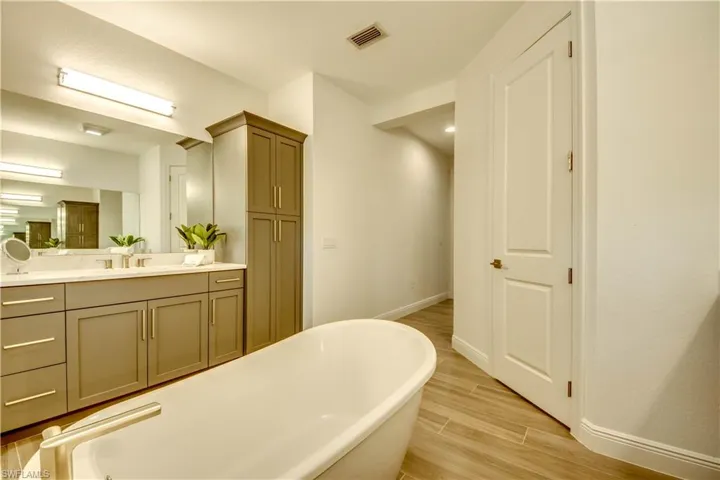 Bathroom featuring vanity, a freestanding tub, and wood finish floors