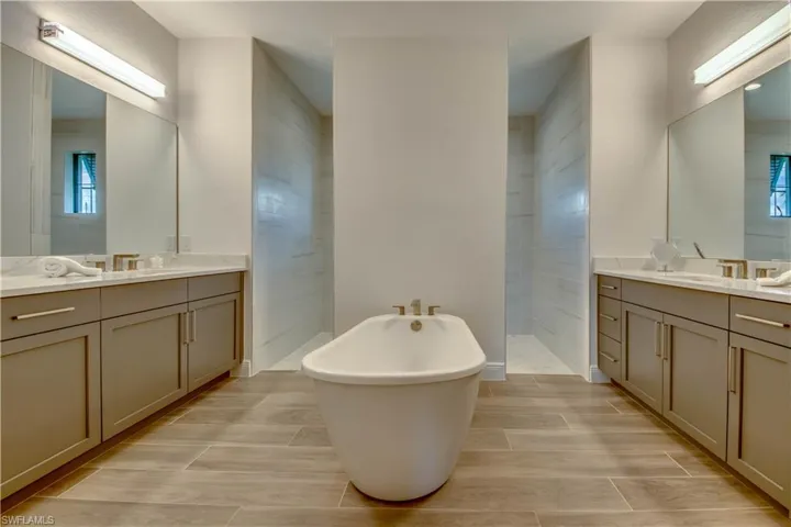 Bathroom with a soaking tub, two vanities, plenty of natural light, and walk in shower