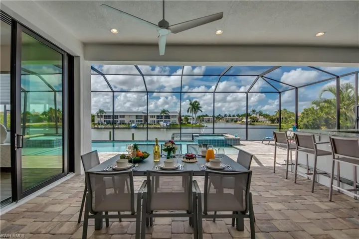 View of patio / terrace featuring a sunroom, outdoor dining area, a water view, and a ceiling fan