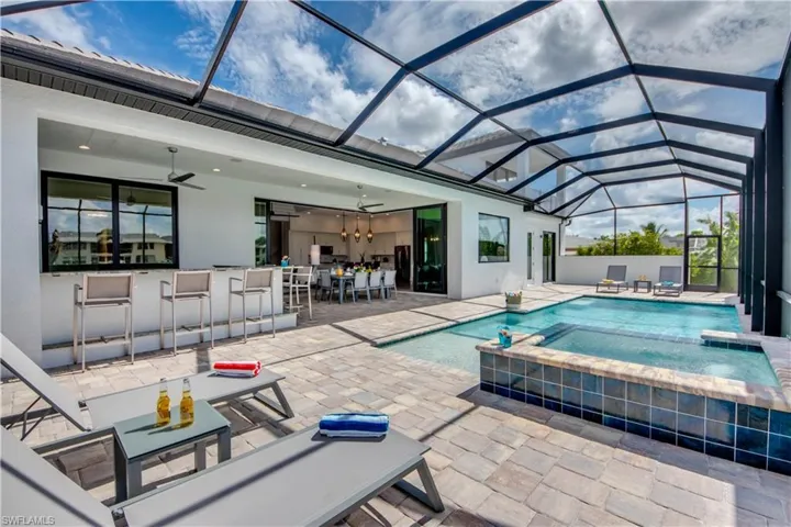 View of pool with a sunroom, glass enclosure, a patio, and a pool with connected hot tub