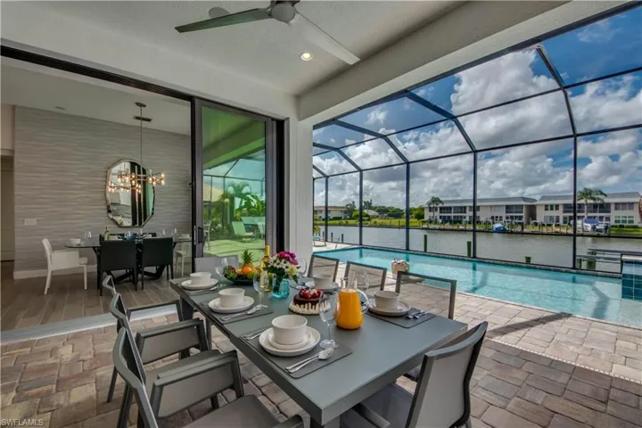 View of patio featuring outdoor dining space, an outdoor pool, a sunroom, a lanai, and a water view