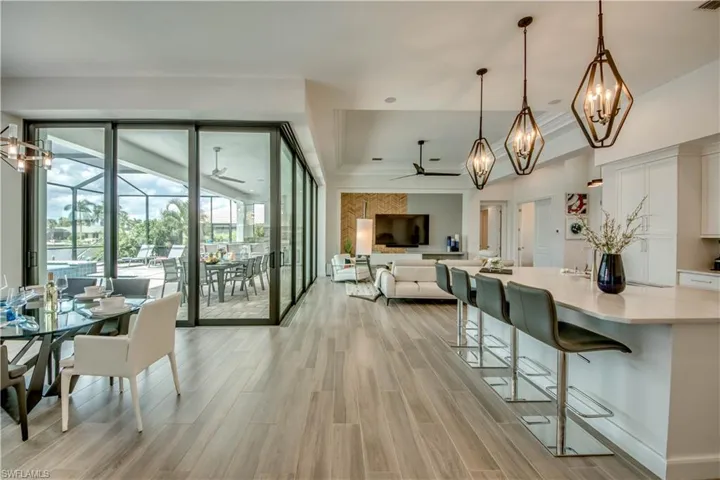 Dining area with a chandelier, wood tiled floors, ornamental molding, a ceiling fan, and a raised ceiling