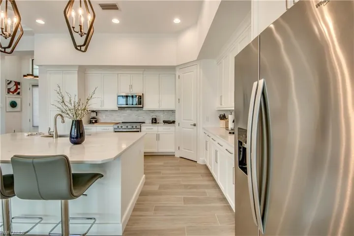 Kitchen featuring appliances with stainless steel finishes, white cabinetry, wood tiled floors, hanging light fixtures, and recessed lighting