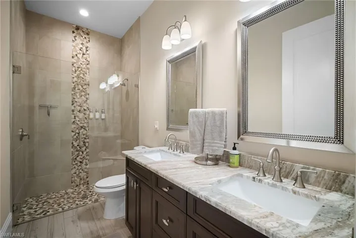 Bathroom featuring double vanity, a stall shower, and light wood-style floors