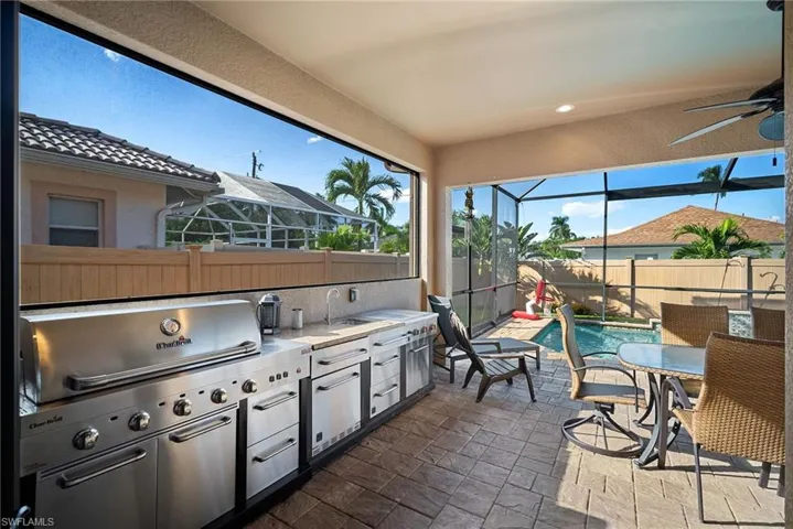 Fenced backyard with exterior kitchen, a patio area, a lanai, a sunroom, and outdoor dining space