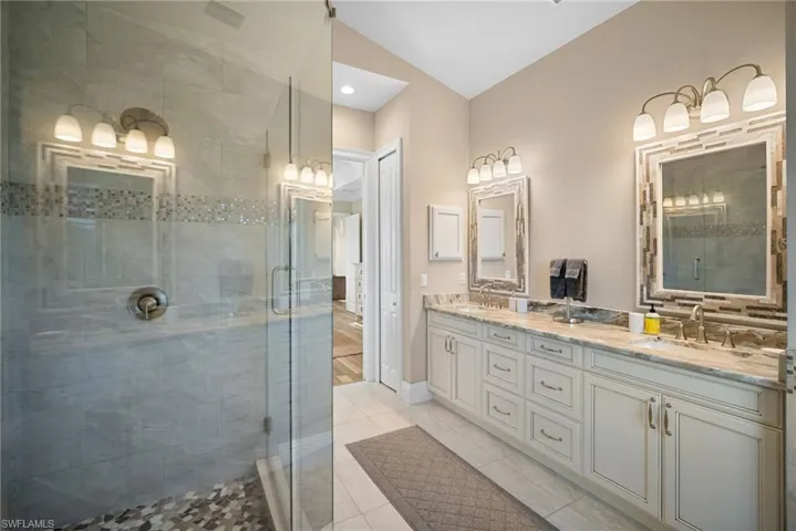 Bathroom featuring double vanity, a stall shower, light tile patterned flooring, and recessed lighting