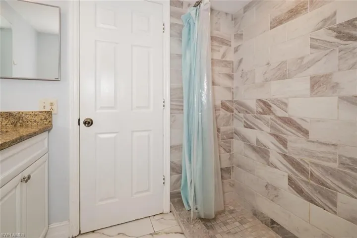Bathroom featuring walk in shower, tile patterned floors, and vanity