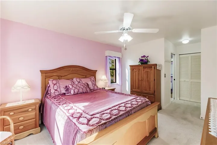 Carpeted bedroom with ceiling fan and a closet