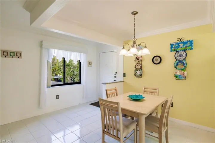 Dining space featuring light tile patterned floors, an inviting chandelier, and crown molding