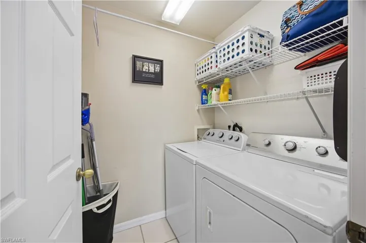 Laundry area with washing machine and dryer and light tile patterned floors