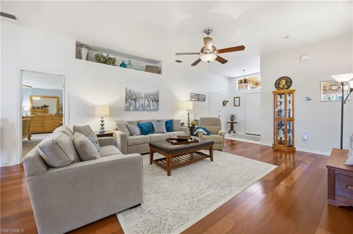 Living room featuring wood-type flooring, ceiling fan, and a high ceiling
