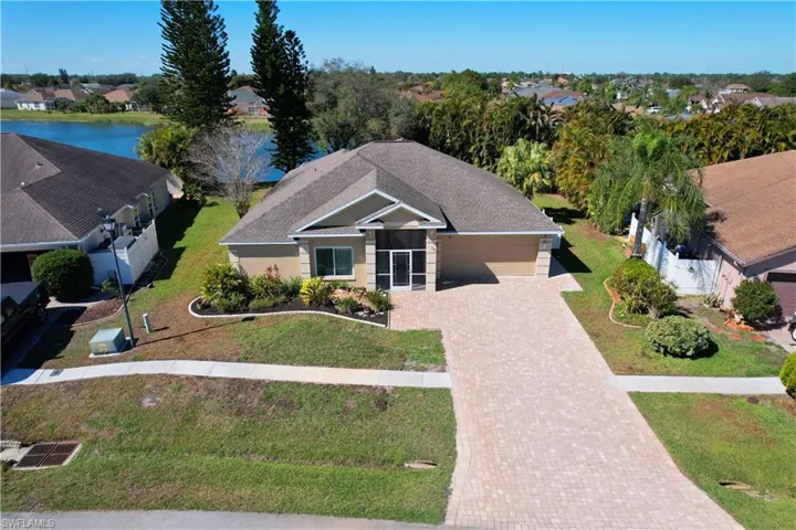 View of front of property with a shingled roof, decorative driveway, a water view, an attached garage, and a front yard