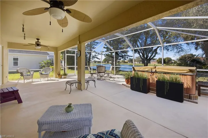 View of patio / terrace featuring a hot tub, a sunroom, a water view, a lanai, and a ceiling fan