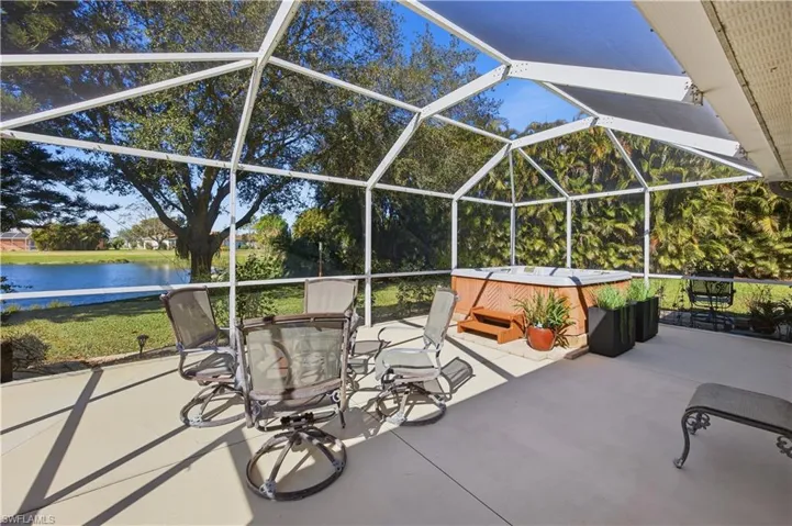 View of patio / terrace with a hot tub, glass enclosure, a sunroom, a water view, and outdoor dining area