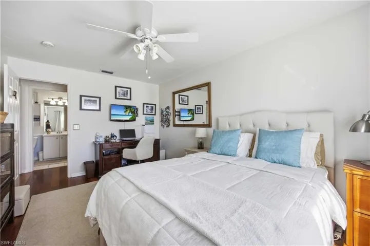 Bedroom with a ceiling fan, dark wood-style floors, and a desk
