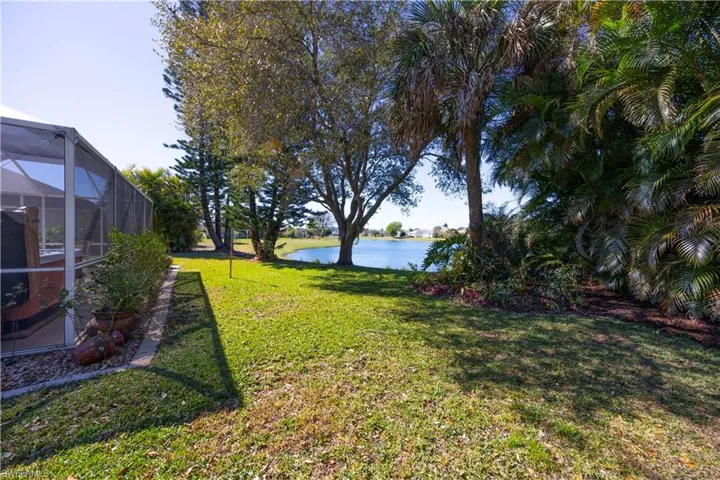 View of green lawn featuring a water view, a lanai, and a sunroom