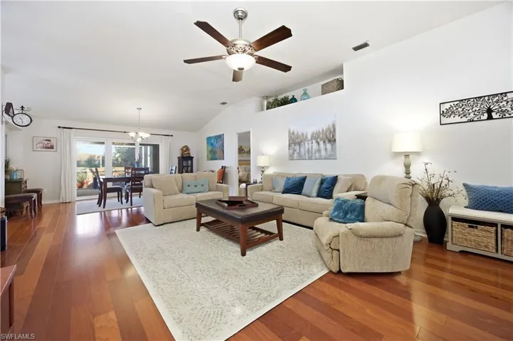 Living area featuring dark wood-style flooring, ceiling fan, vaulted ceiling, and hanging lights