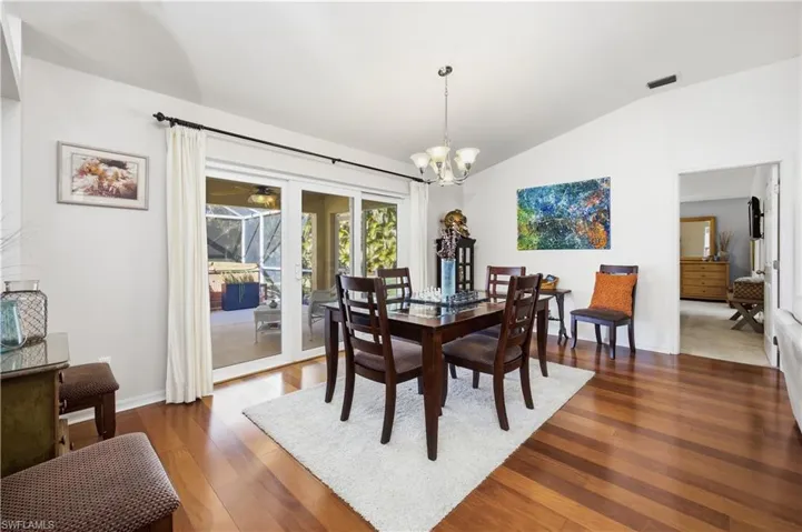 Dining space with dark wood-style flooring, hanging lights, lofted ceiling, and ceiling fan