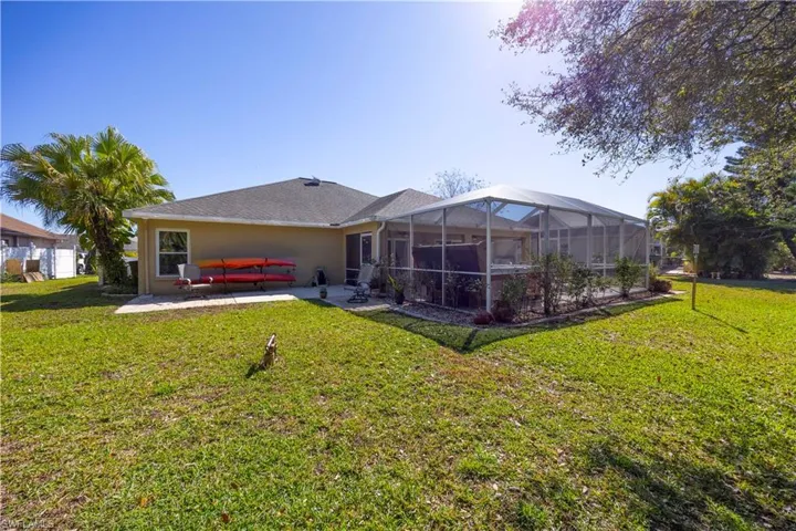 Rear view of house with a sunroom, a lawn, a lanai, stucco siding, and a patio area