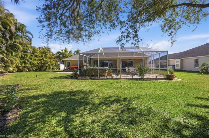 Back of house with a lanai, a sunroom, a lawn, and a patio area