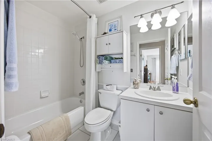 Bathroom featuring vanity, shower / bath combo with shower curtain, and light tile patterned floors