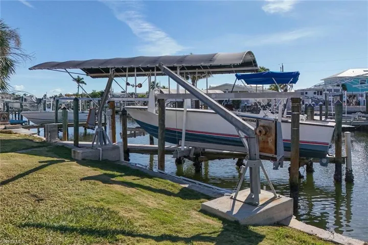 Dock area with boat lift, a yard, and a water view