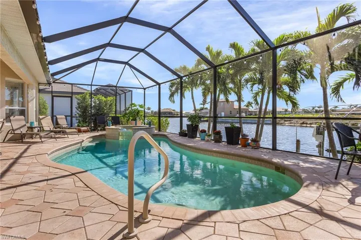 View of swimming pool featuring a water view, glass enclosure, and a patio area